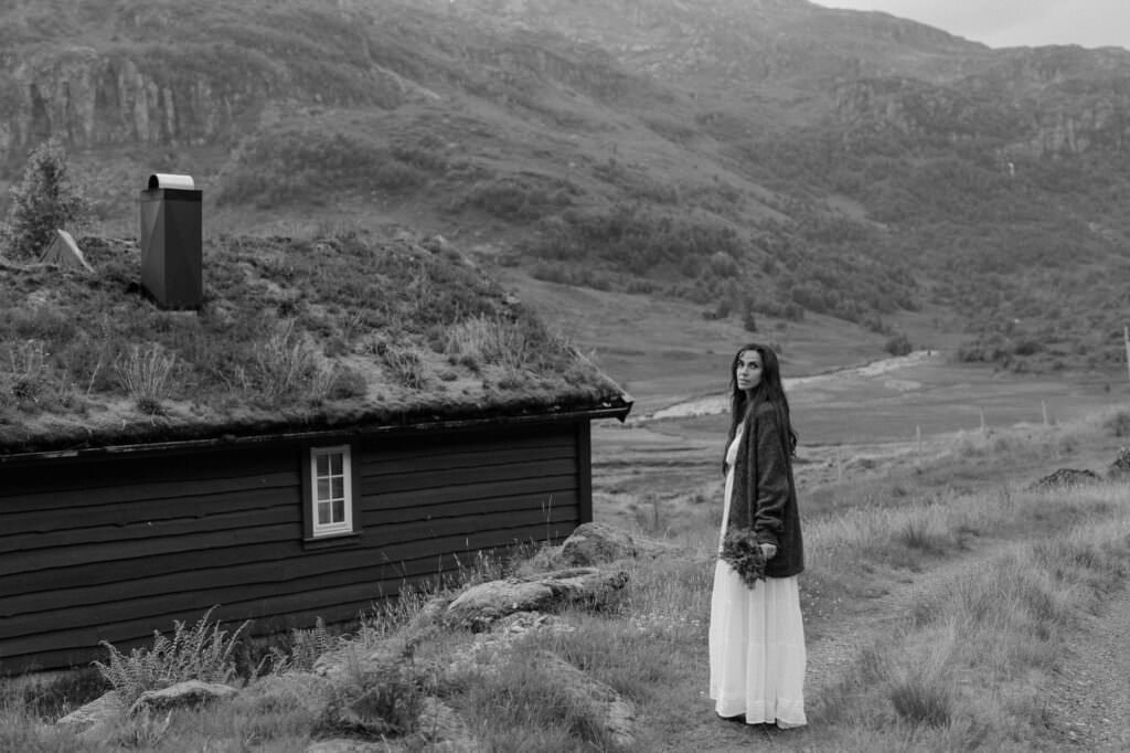 A bride standing in front of a traditional Norwegian cabin