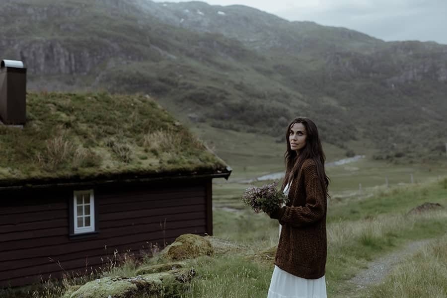 A bride standing in front of a traditional Norwegian cabin